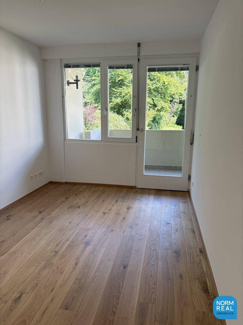 Helles Schlafzimmer mit Holzboden und direktem Zugang zu einem kleinen Balkon.