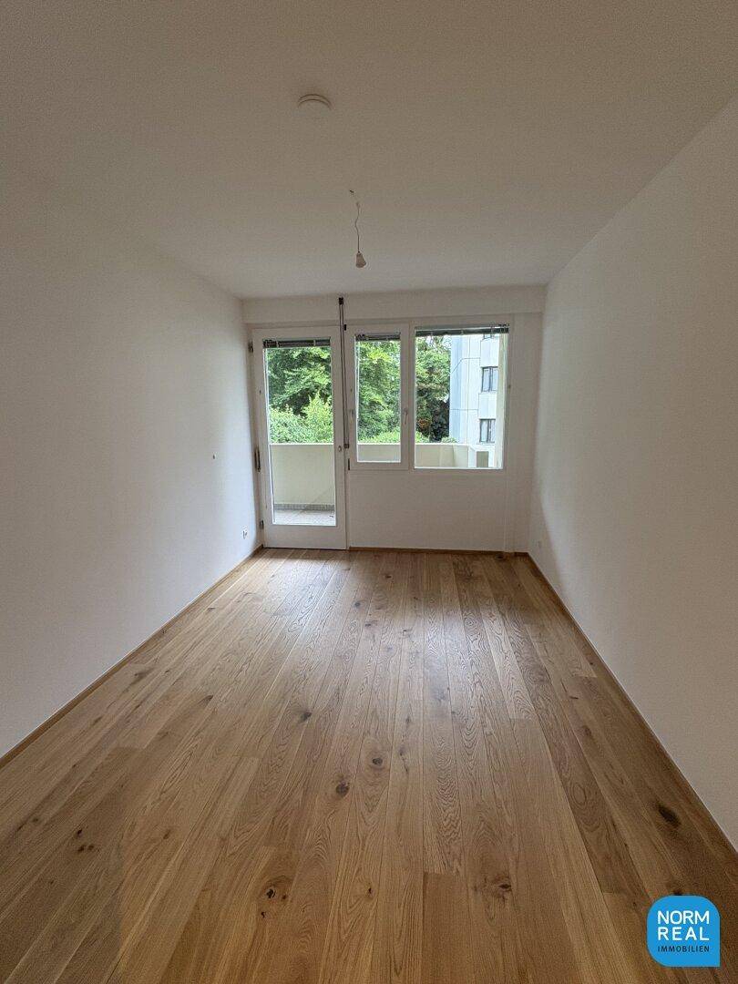 Helles Schlafzimmer mit Holzboden und direktem Zugang zu einem kleinen Balkon.