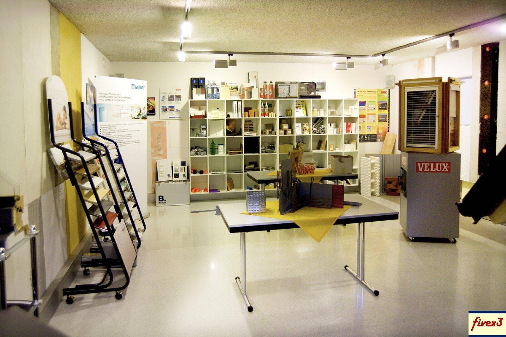 Heller Ausstellungsraum mit Regalen voller Produktmuster und Informationsmaterialien.