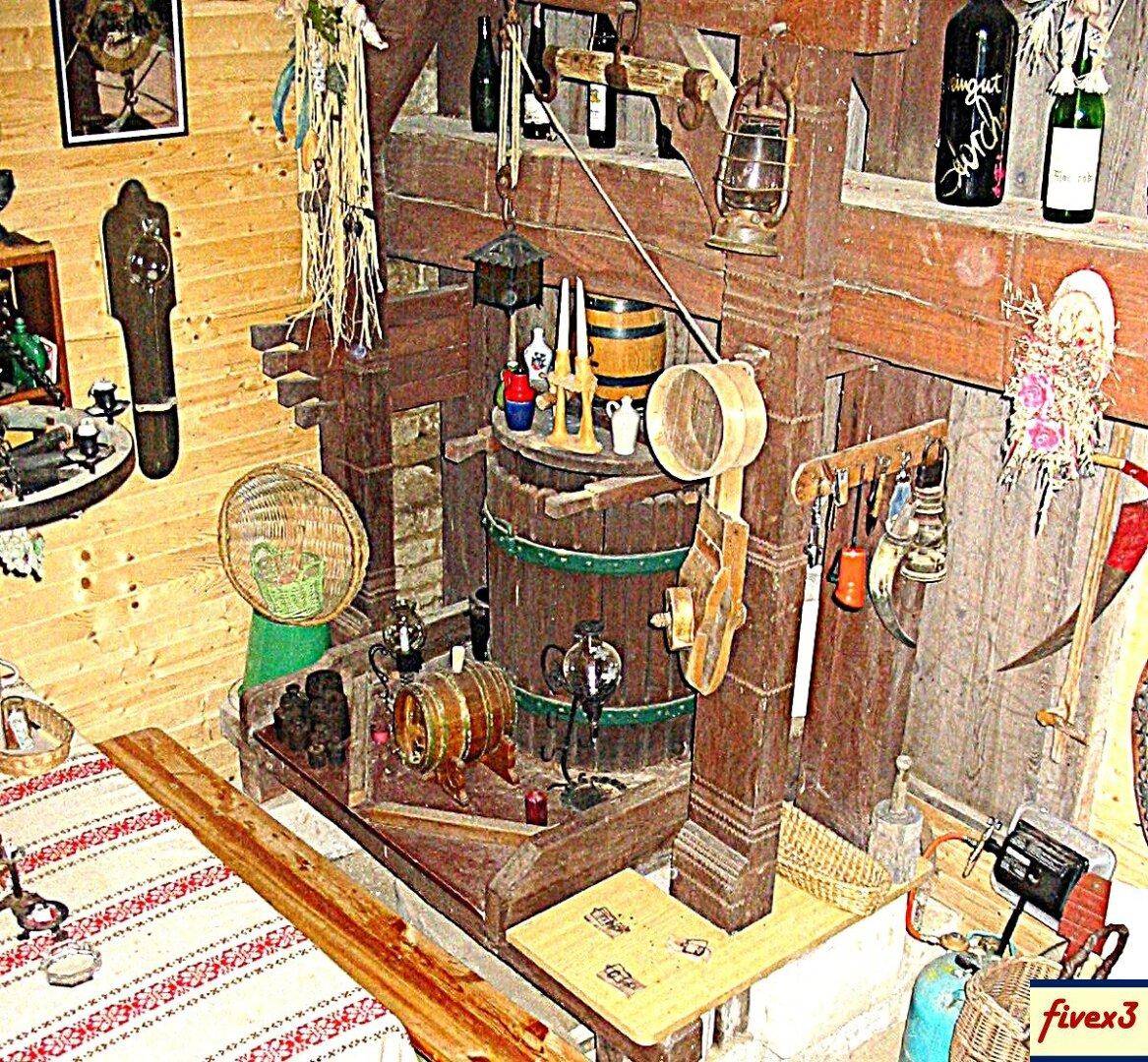 Blick auf einen rustikalen Innenraum mit einem gedeckten Tisch und einer großen Holzkonstruktion, umgeben von traditionellen Gegenständen.