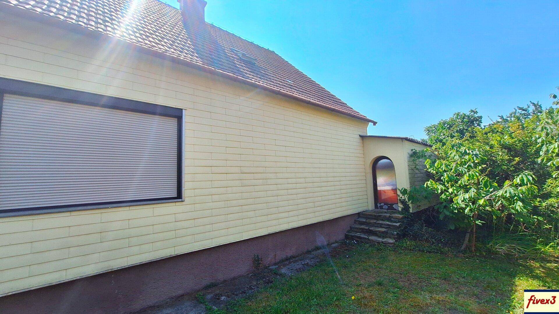 Seitenansicht des Hauses mit Rollladenfenster und einem überdachten Eingangsbereich.