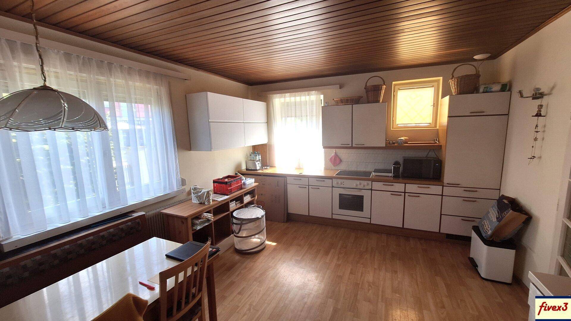 Helle Küche mit Holzboden, weißen Schränken und einer Holzdecke.