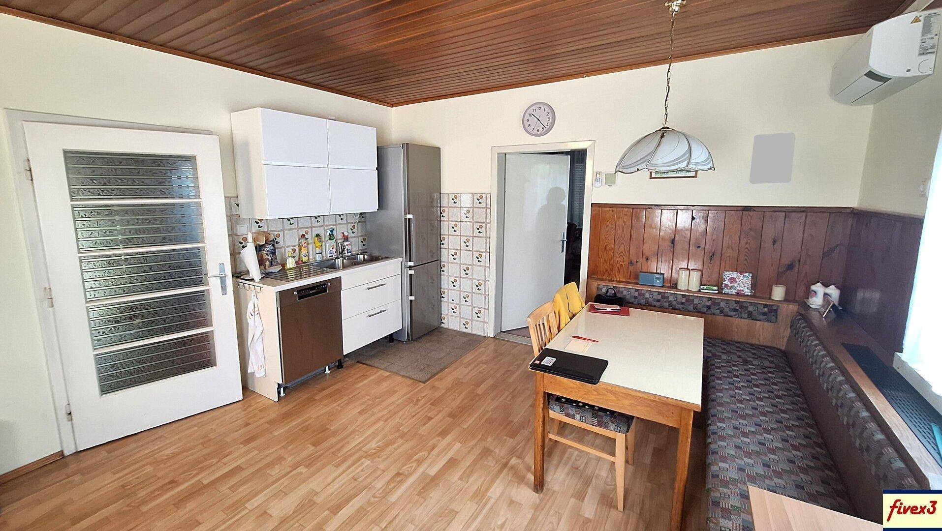Geräumige Küche mit Holzboden, Essbereich und traditioneller Holzvertäfelung.