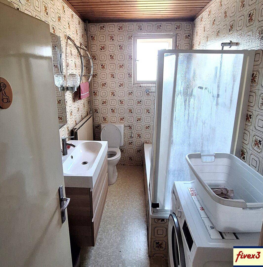 Badezimmer mit gemusterten Fliesen, Waschbecken, Toilette und Duschbereich.