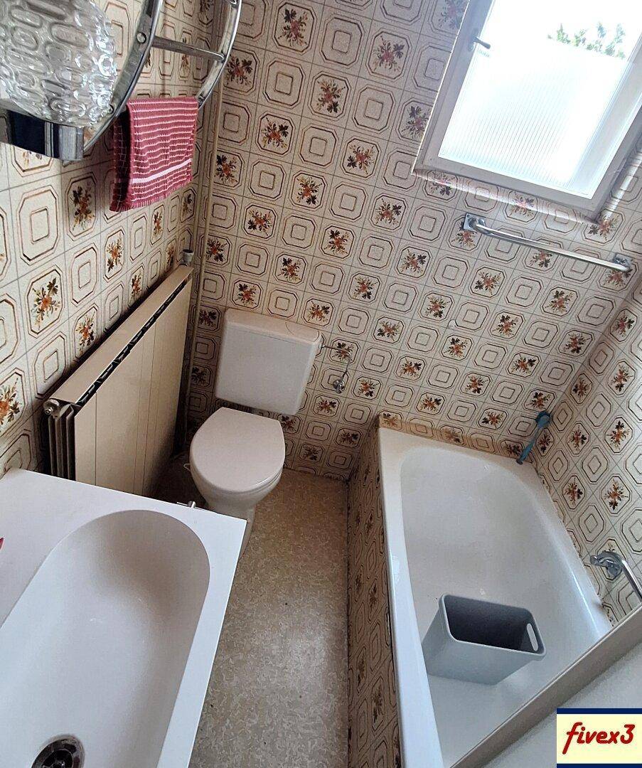 Badezimmer mit Badewanne, Waschbecken und gemusterten Wandfliesen im Retro-Stil.