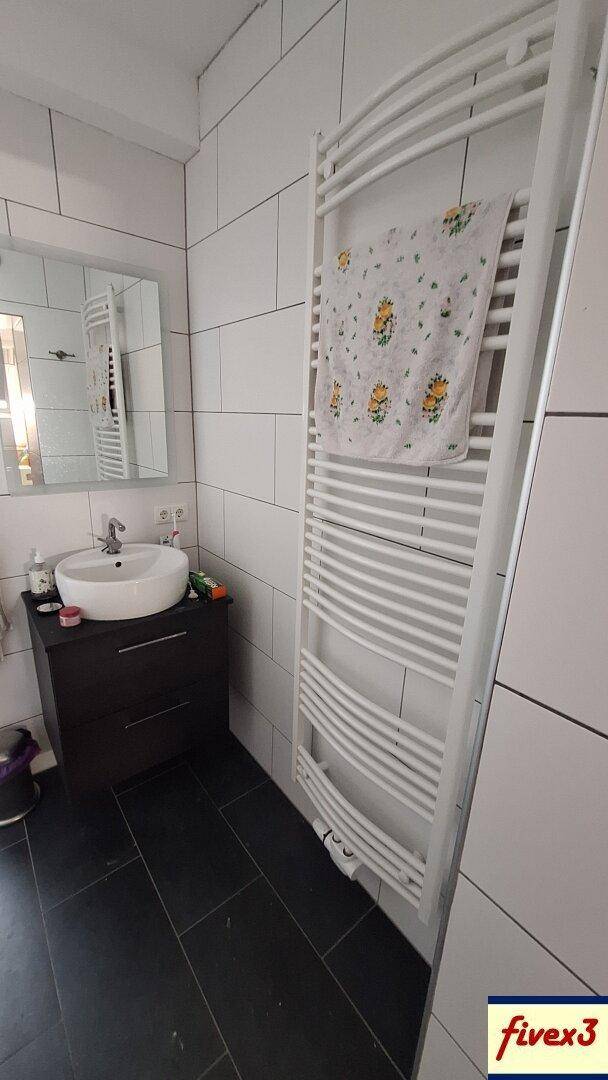 Waschbecken mit Spiegel und beheiztem Handtuchhalter in einem modernen Badezimmer.
