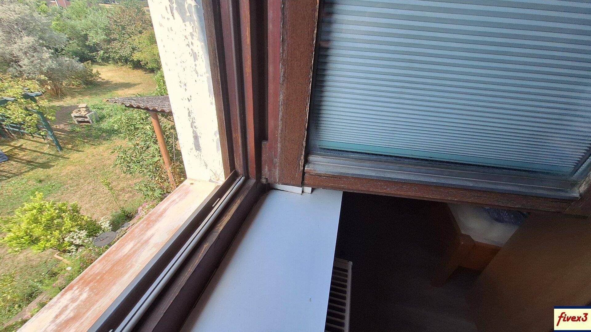Alter Fensterrahmen mit Blick auf den Garten und die umliegende grüne Landschaft.