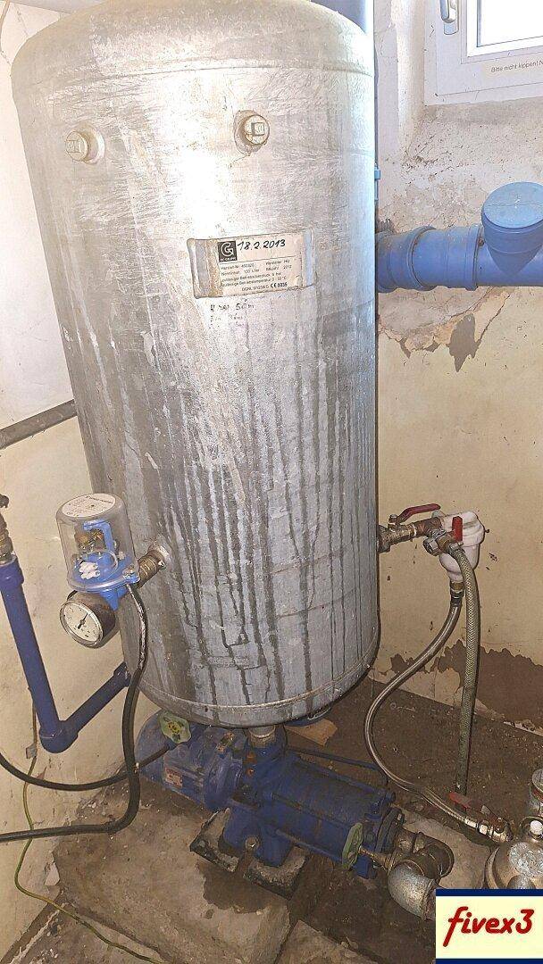 Kellerraum mit großem Druckbehälter, Pumpe und Rohrleitungen für die Wasserversorgung.