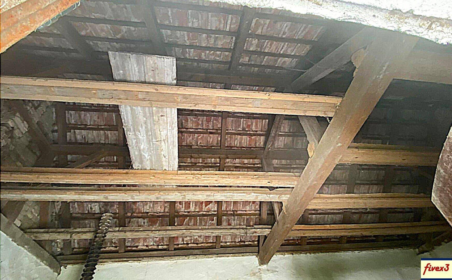 Blick auf die freiliegende Dachkonstruktion mit Holzbalken und Ziegeln, die das rustikale Ambiente unterstreicht.