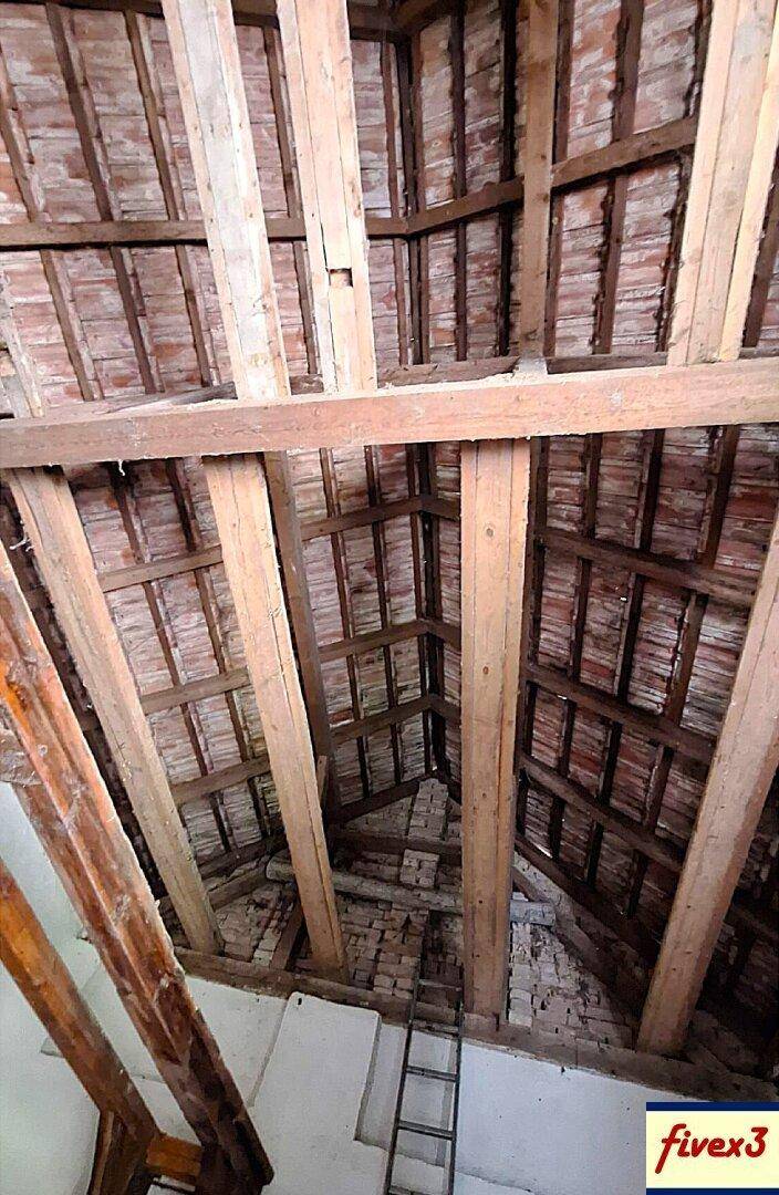 Freiliegende Holzbalken und Ziegel der Dachkonstruktion, die die traditionelle Bauweise des Gebäudes zeigen.