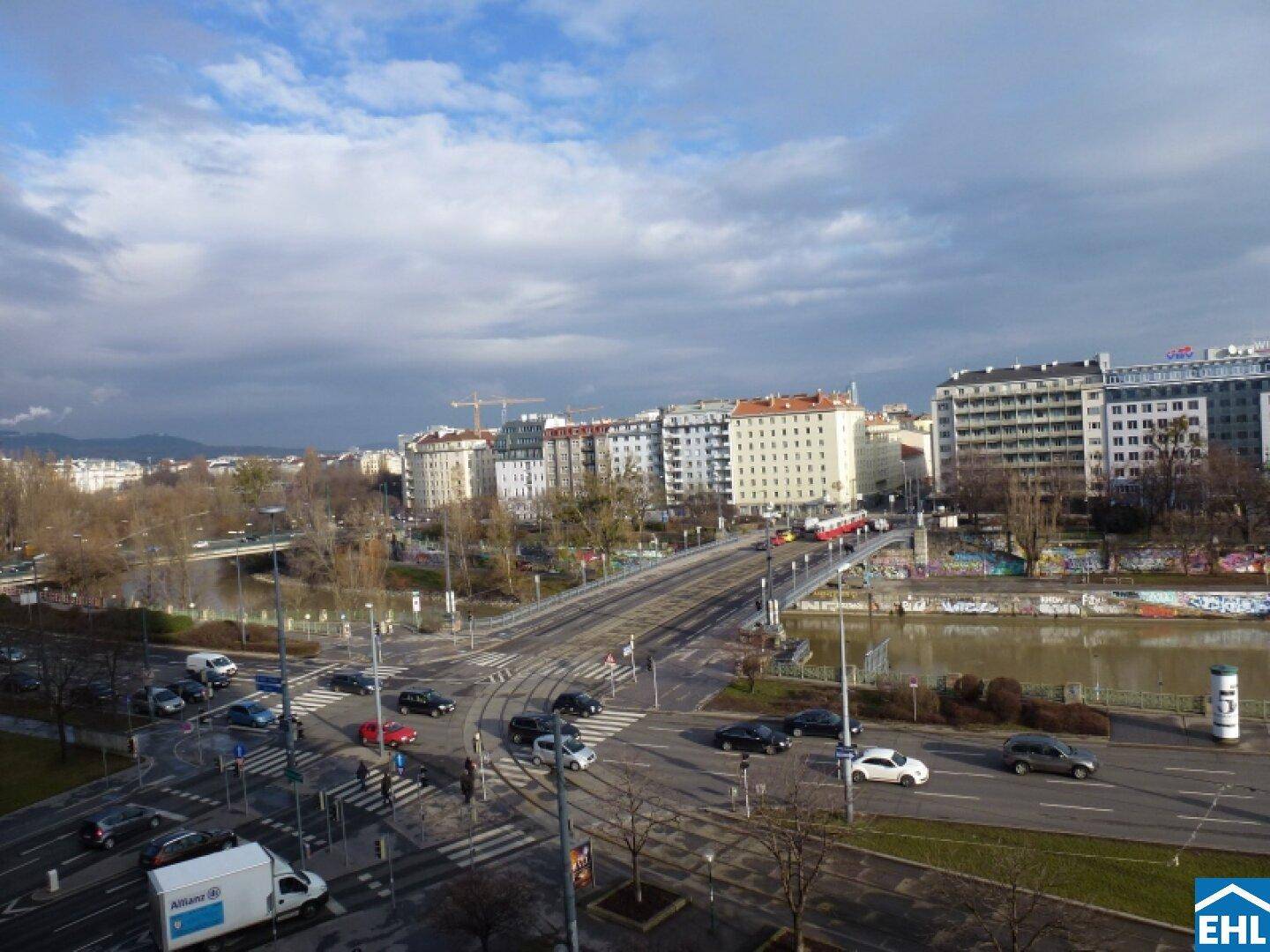 Weitläufiger Blick auf eine Stadtbrücke, den Fluss und die umliegende Stadtlandschaft.