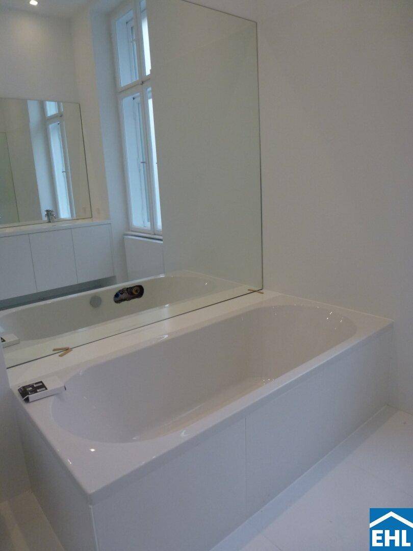 Elegantes Badezimmer mit integrierter Badewanne und großem Wandspiegel.