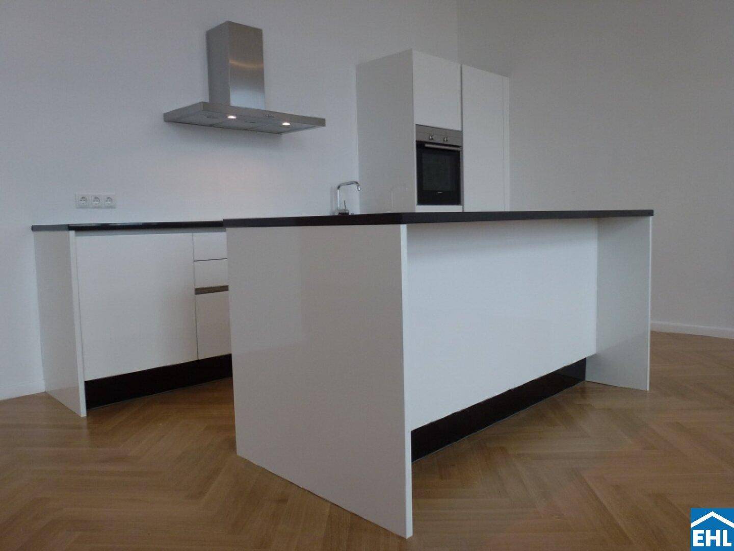 Moderne weiße Einbauküche mit Kochinsel, integriertem Backofen und Dunstabzugshaube.