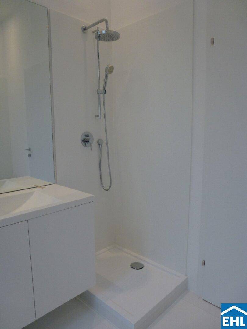 Detaillierte Ansicht der modernen Dusche mit Regenduschkopf und flacher Duschwanne.