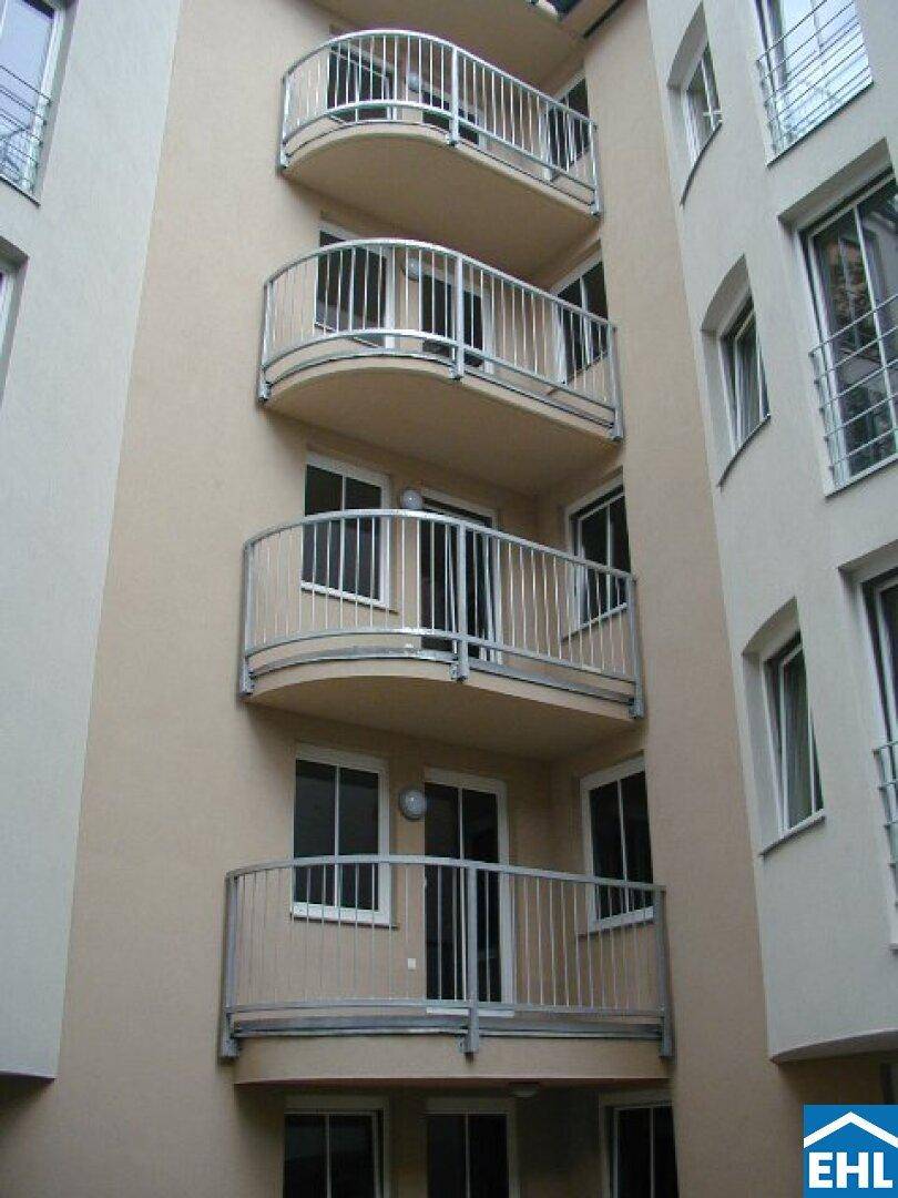 Mehrere geschwungene Balkone mit modernen Metallgeländern an der Gebäudefassade.