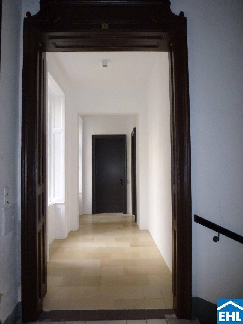 Eingangsbereich mit dunklem Holztürrahmen, der in einen hellen Flur führt.