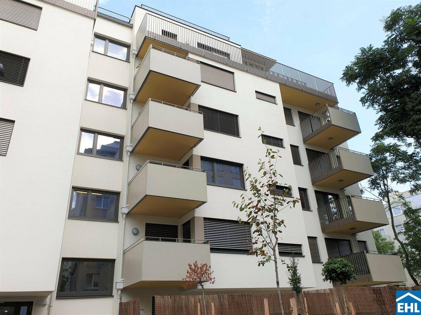 Moderne Wohnhausfassade mit zahlreichen Balkonen und großen Fenstern.