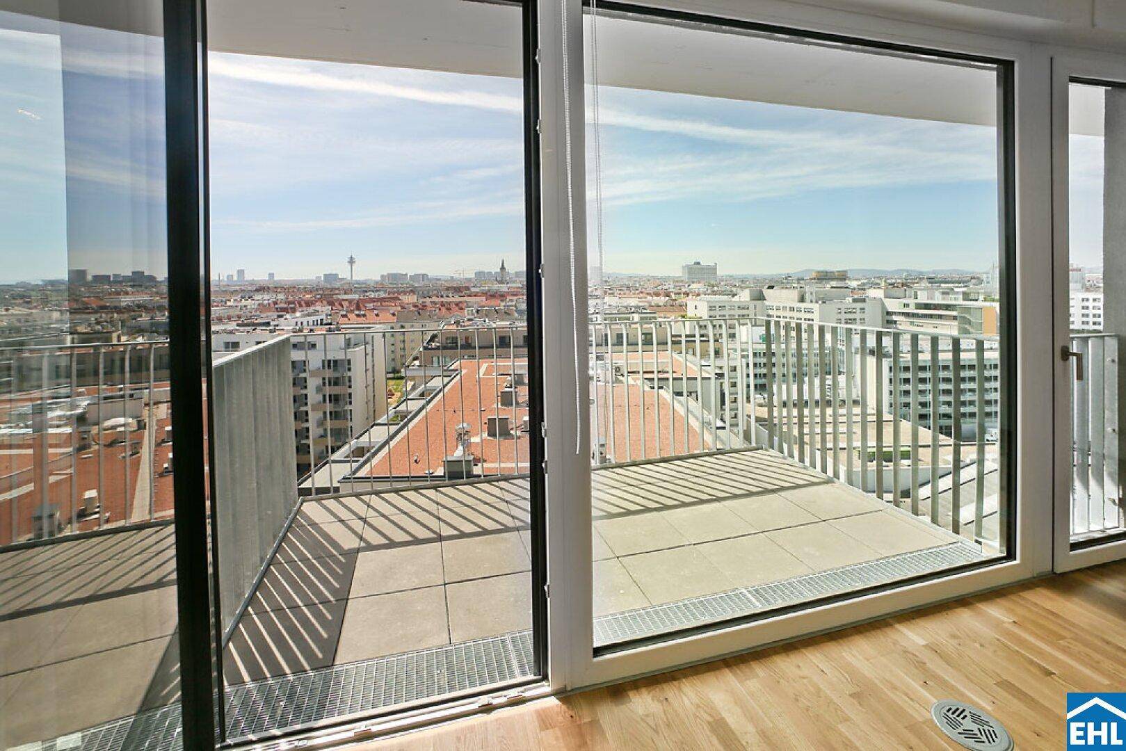 Heller Wohnraum mit großzügigen Fenstern, die einen weiten Blick über die Stadt bieten.