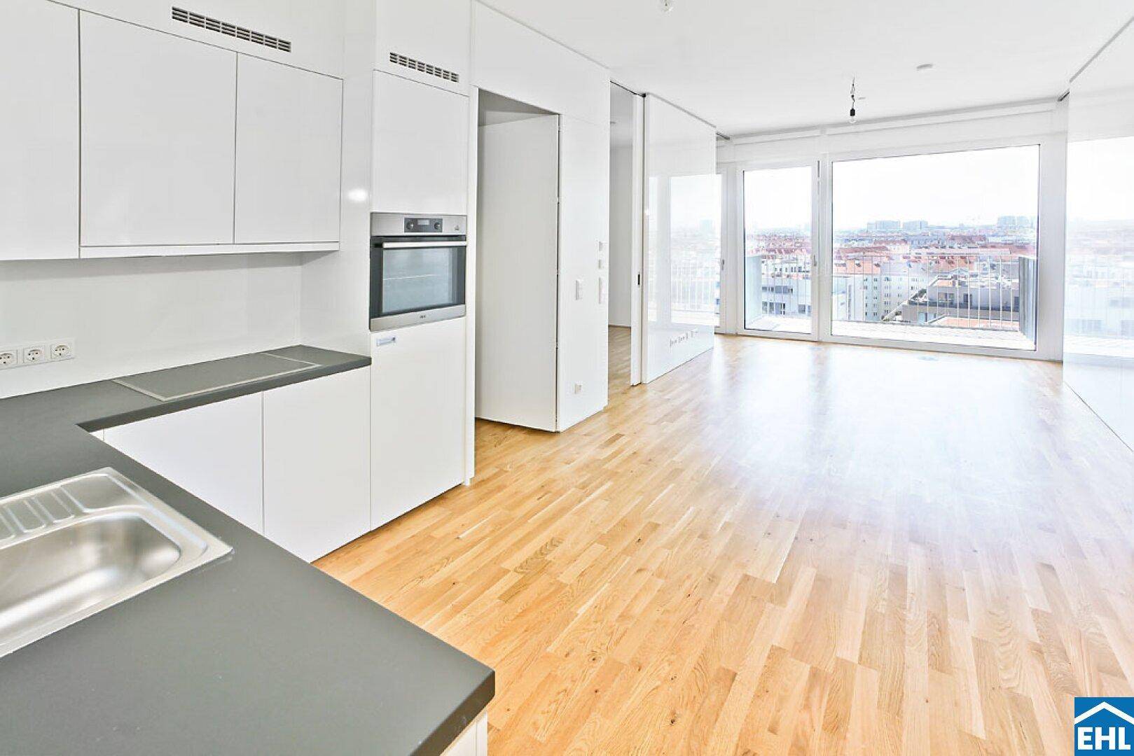 Moderne Einbauküche mit weißen Schränken, dunkler Arbeitsplatte und integrierten Geräten.