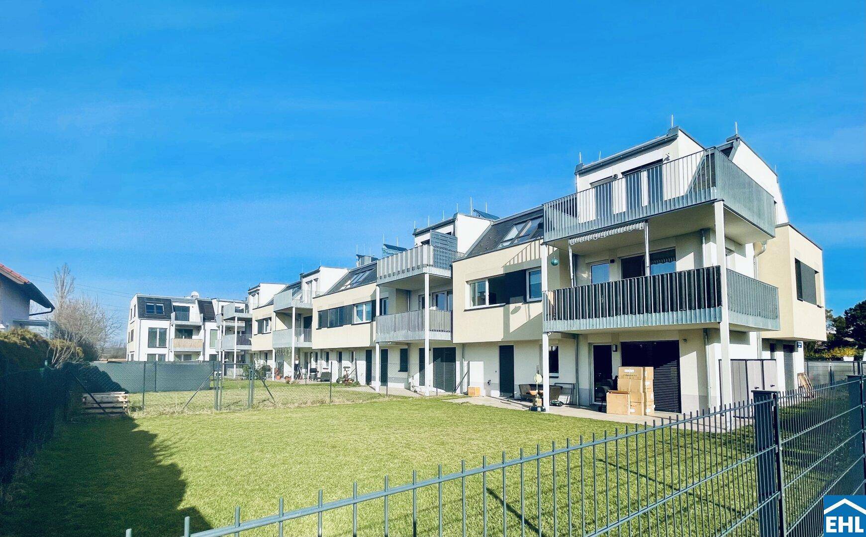 Rückseite der modernen Wohnanlage mit privaten Gärten, Balkonen und weitem Blick ins Grüne.