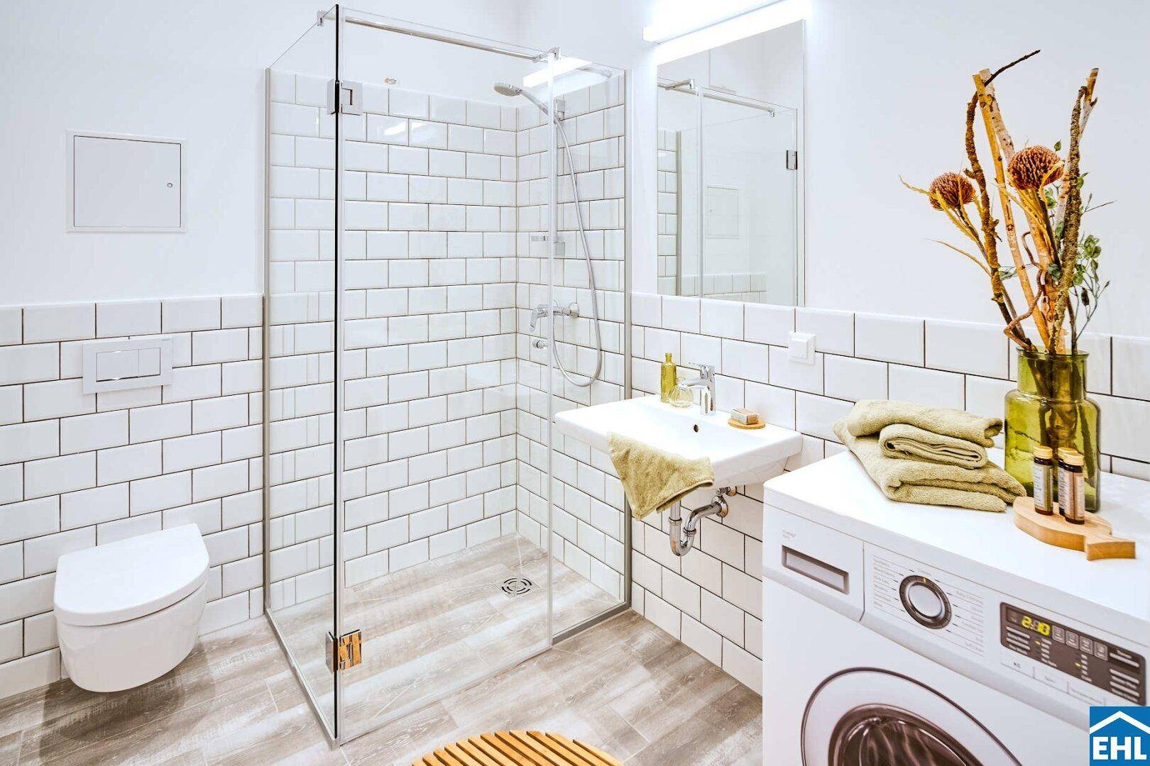 Modernes Badezimmer mit ebenerdiger Dusche, WC, Waschbecken und Waschmaschine.