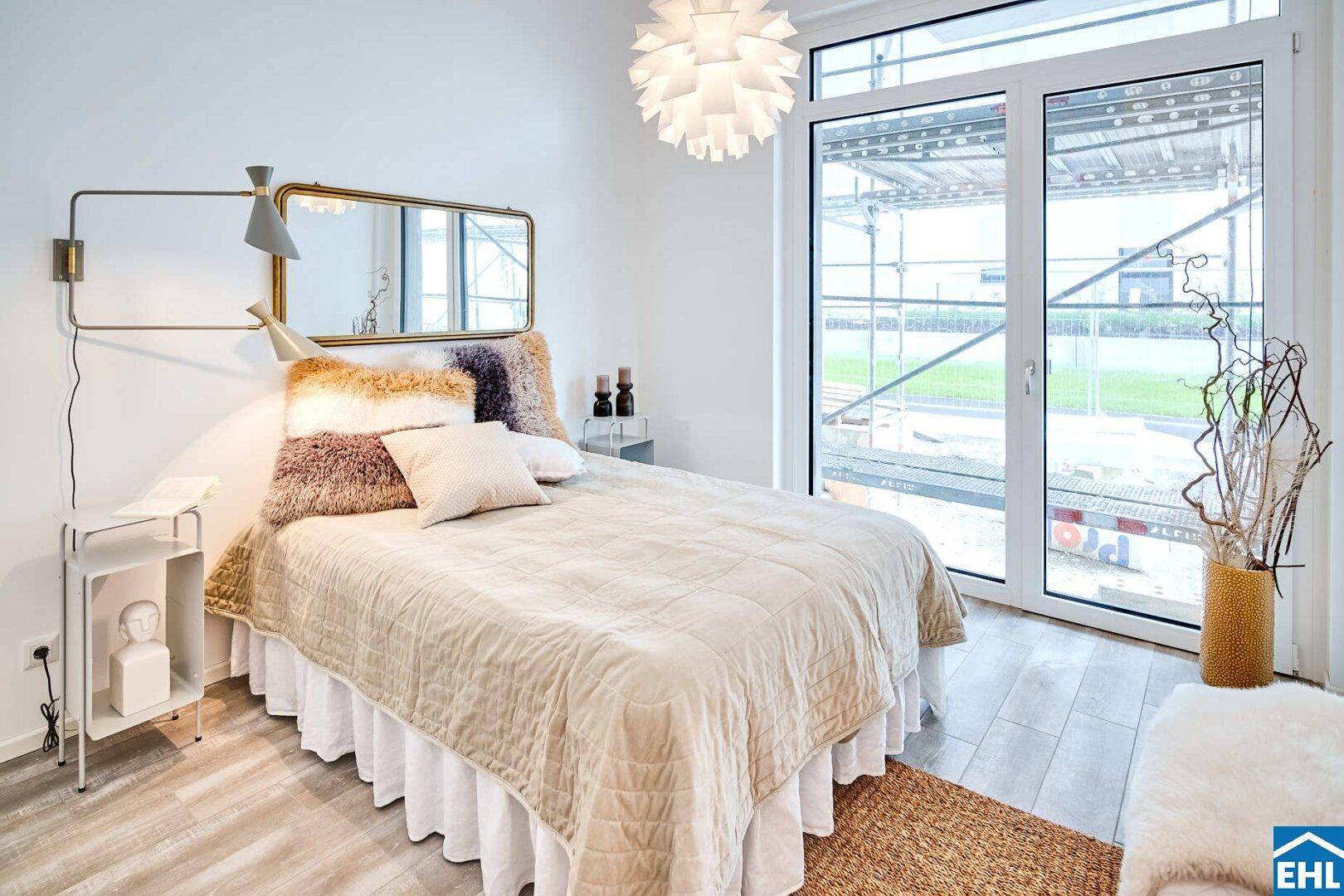 Helles Schlafzimmer mit Doppelbett, modernem Spiegel und großem Fenster.