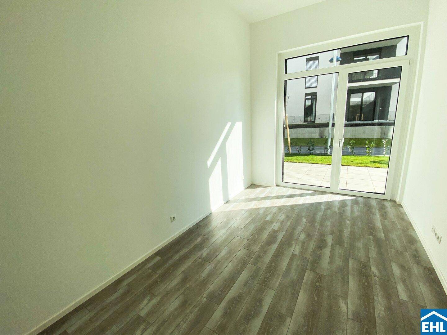 Heller Raum mit großen Fenstern und Holzboden, ideal als Wohn- oder Schlafzimmer.