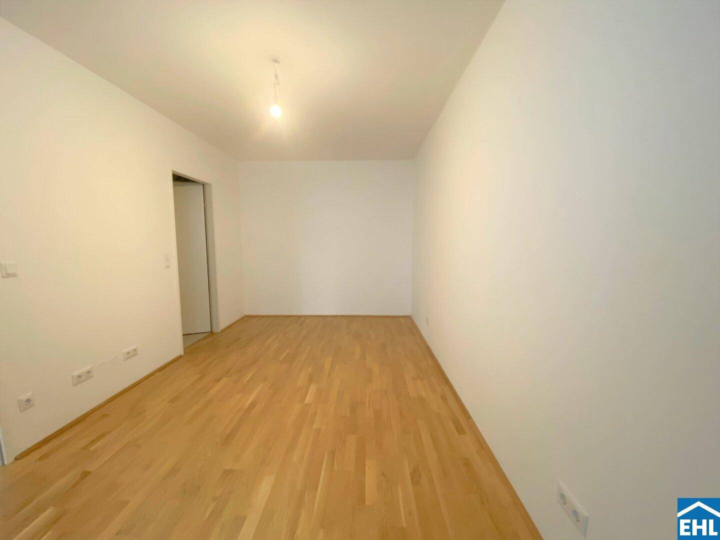 Leeres Zimmer mit hellem Parkettboden und weißen Wänden, bereit zur individuellen Gestaltung.