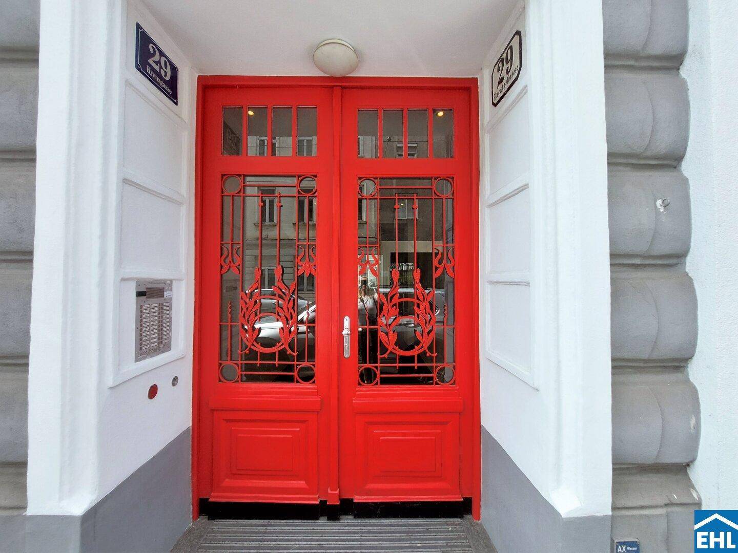 Auffällige rote Eingangstür mit kunstvollen Gittern und Hausnummer 29.
