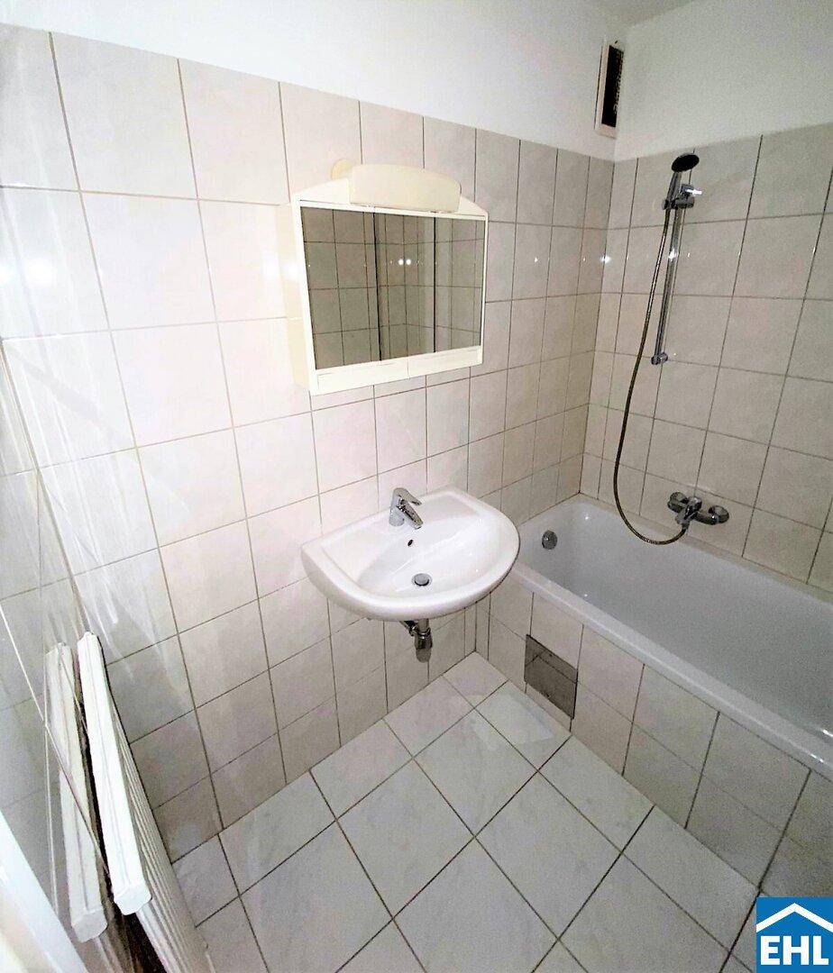 Gefliestes Badezimmer mit Badewanne, Waschbecken und Spiegelschrank, in gutem Zustand.