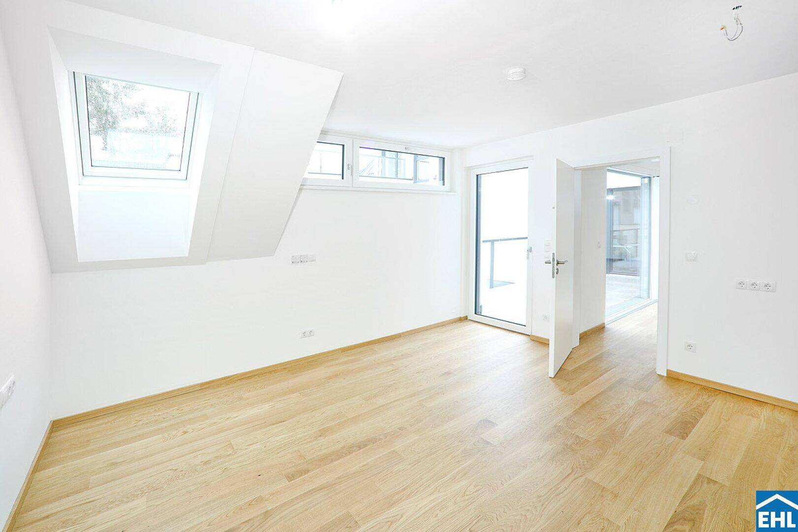Lichtdurchflutetes Zimmer mit Holzboden, Dachfenstern und direktem Zugang zu einem Außenbereich.