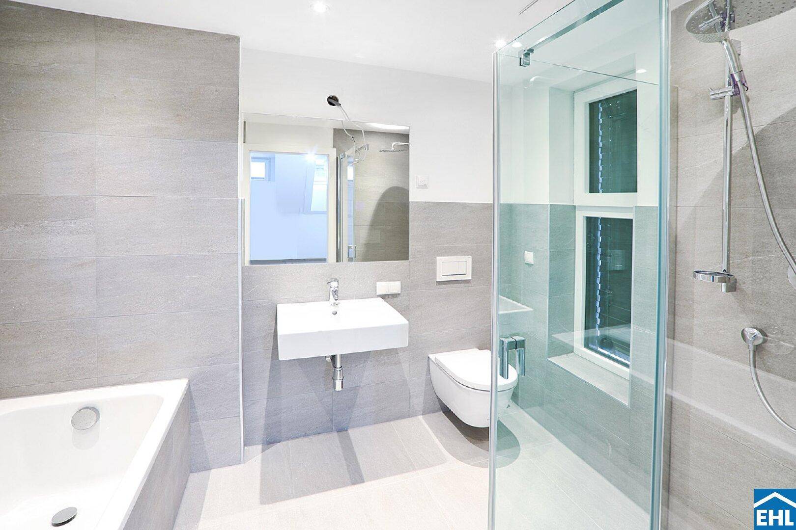 Modernes Badezimmer mit hellgrauen Fliesen, Badewanne, Dusche und Fenster für natürliches Licht.