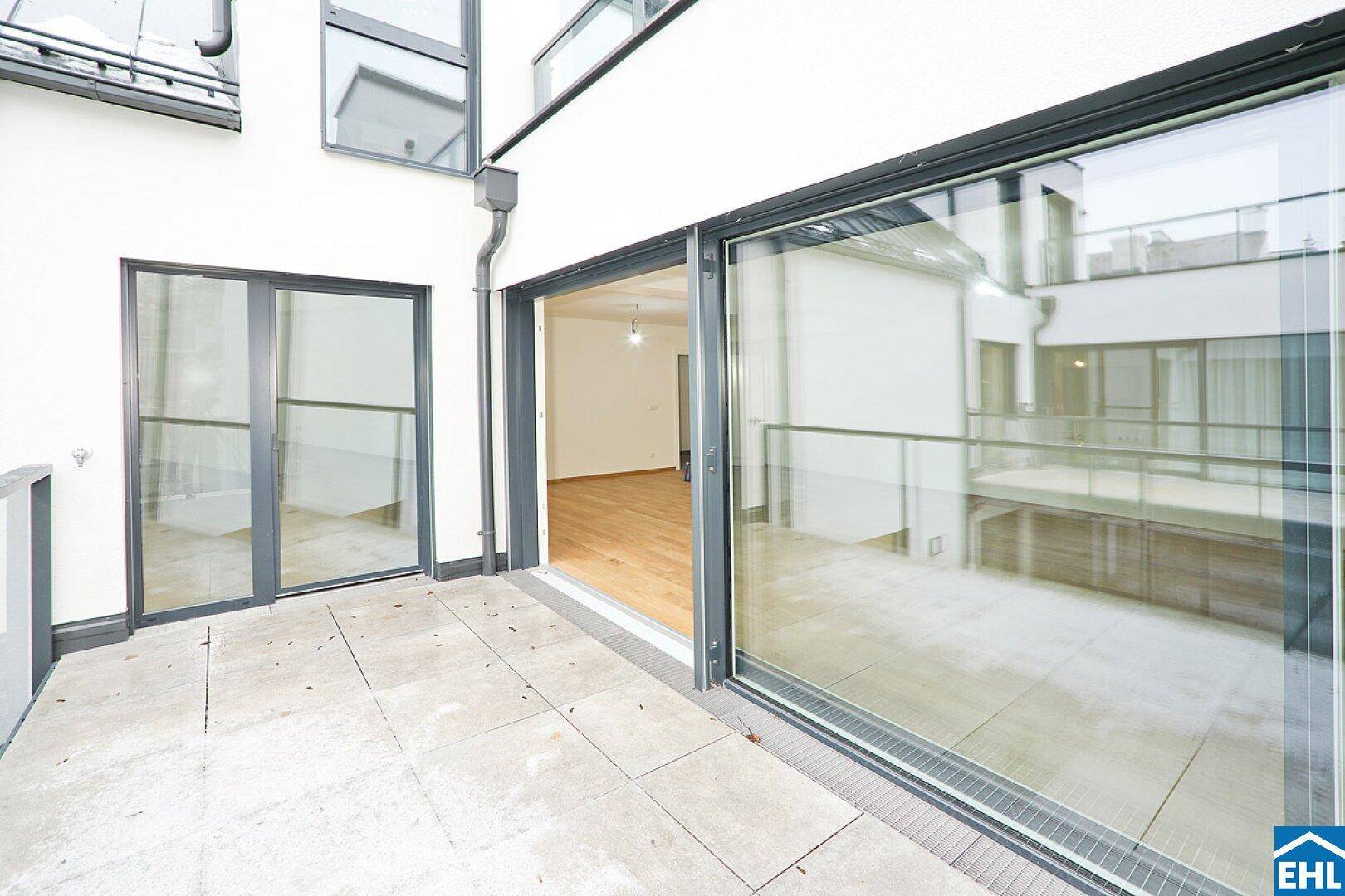 Geräumige Terrasse mit Fliesenboden und Glasgeländer, ideal für entspannte Stunden im Freien.