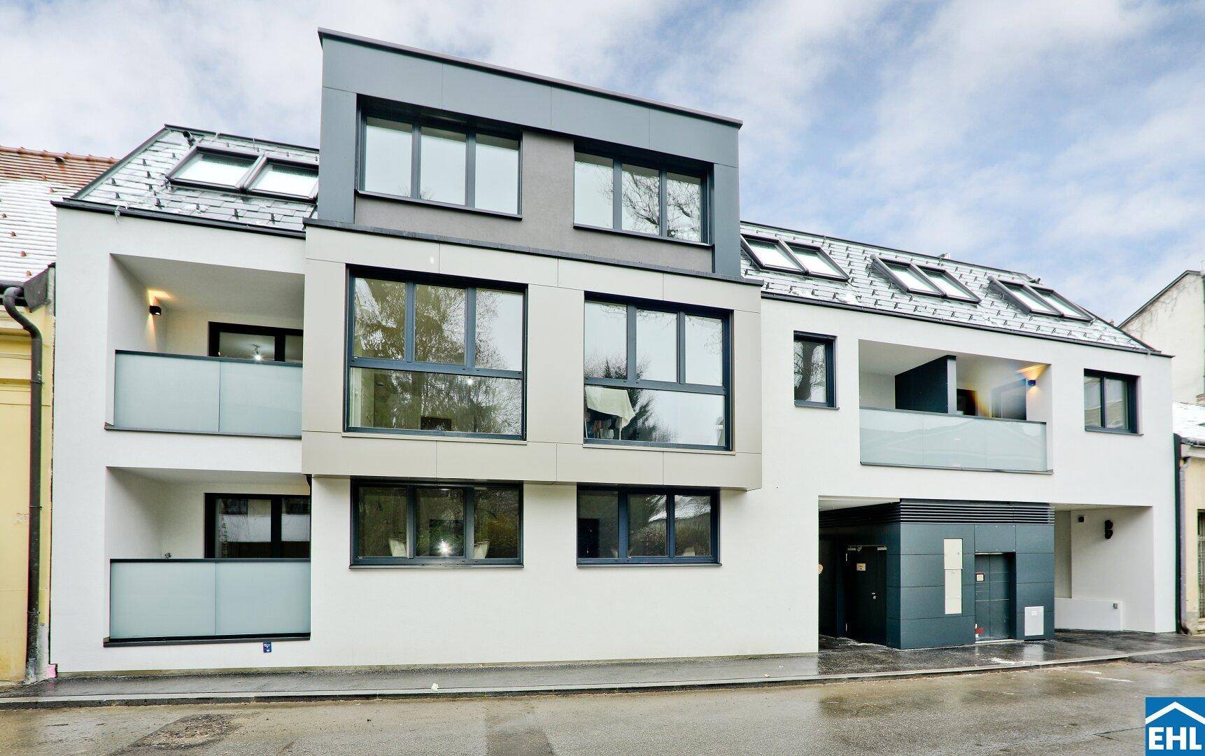 Moderne Wohnanlage mit weißer Fassade, großen Fenstern und Balkonen, die ein zeitgemäßes Design aufweisen.