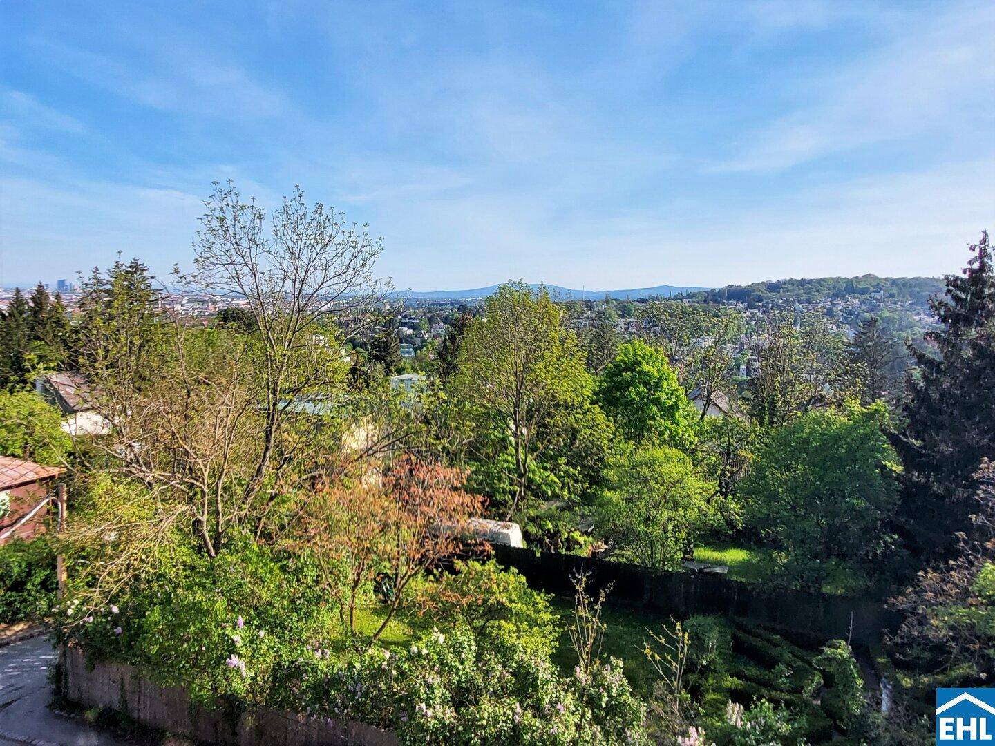 Panoramablick ins Grüne mit weitem Horizont und sichtbarer Stadt in der Ferne.