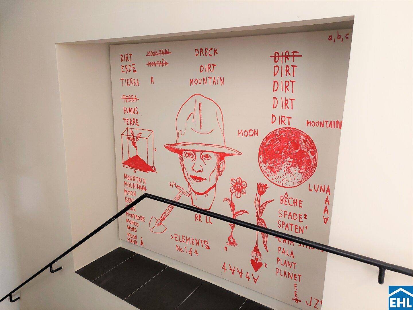 Treppenhaus mit kreativer Wandgestaltung in Rot und schwarzem Handlauf.
