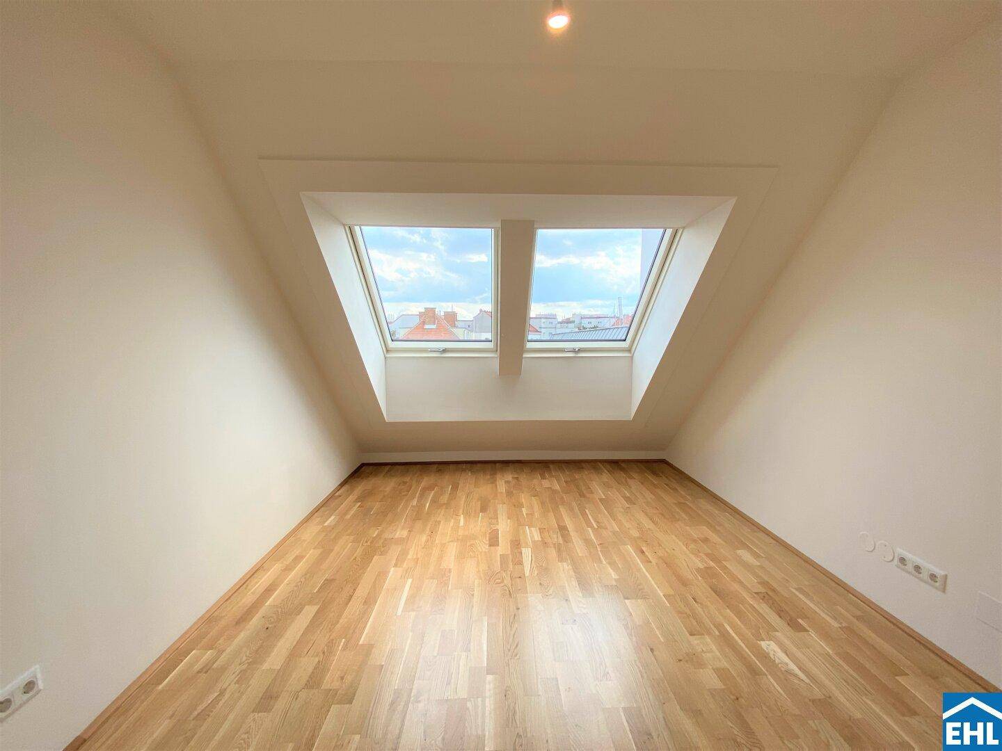 Geräumiges Dachzimmer mit Parkettboden und hellen Dachfenstern, ideal als Schlafzimmer nutzbar.