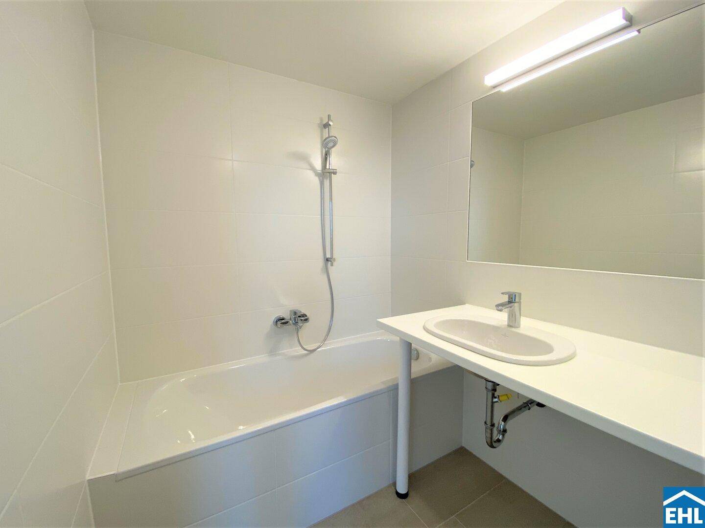 Modernes Badezimmer mit Badewanne, Einzelwaschbecken und weißen Fliesen, in makellosem Zustand.