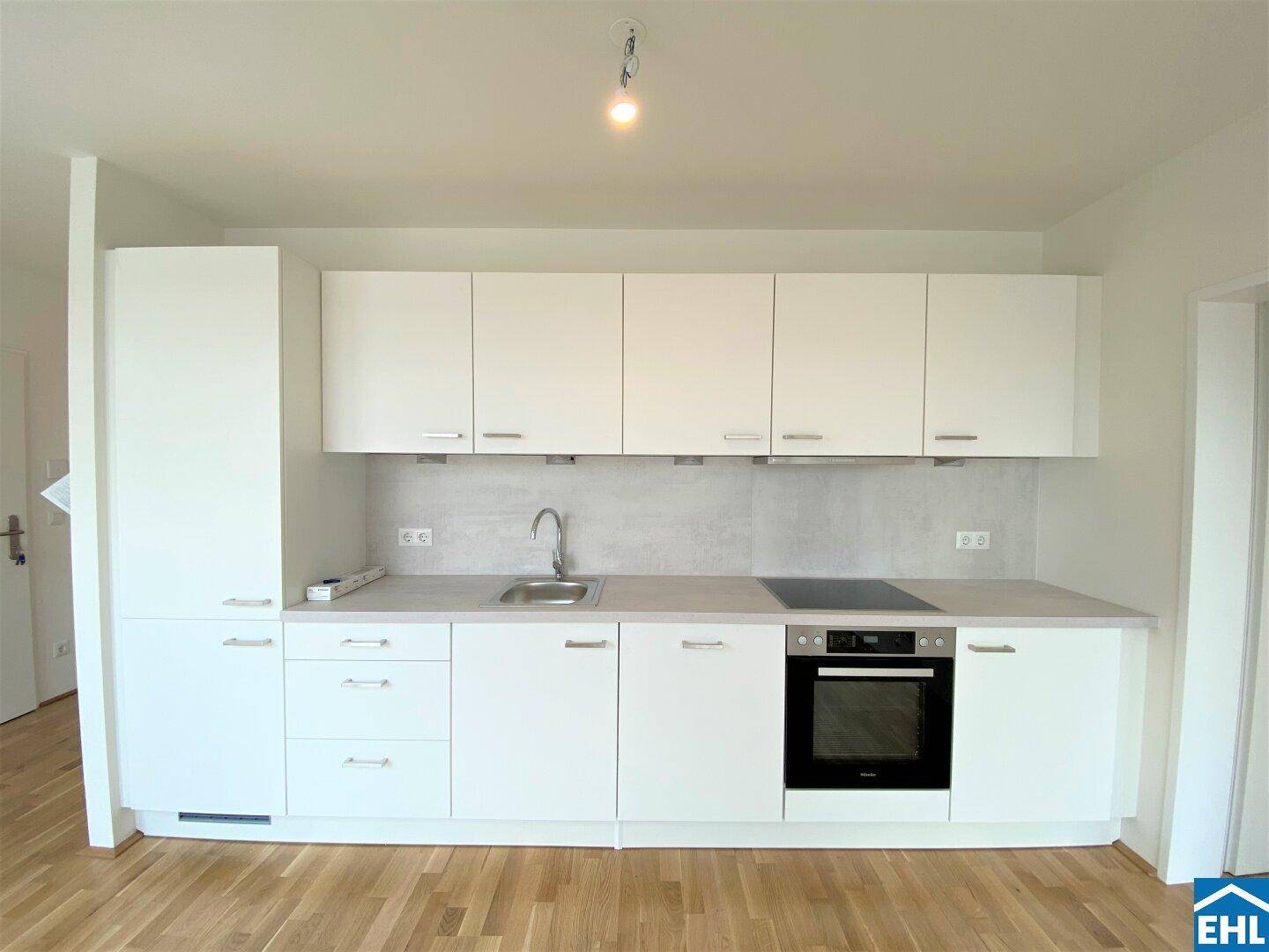 Moderne Einbauküche mit weißen Schränken, Induktionskochfeld und Backofen, in neuwertigem Zustand.