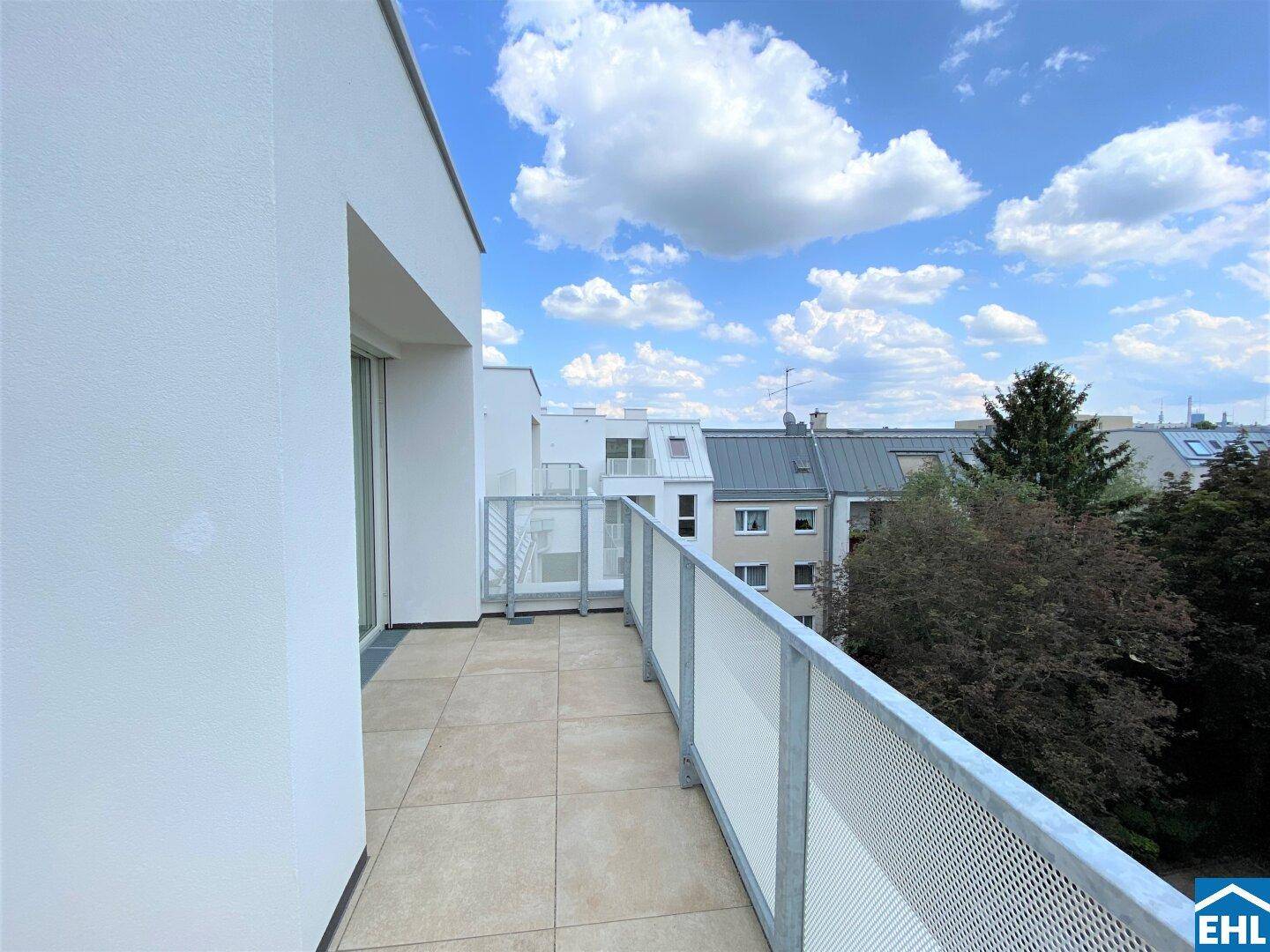 Langer Balkon mit Fliesenboden und moderner Metallbrüstung, bietet einen weiten Blick auf die Nachbarschaft.