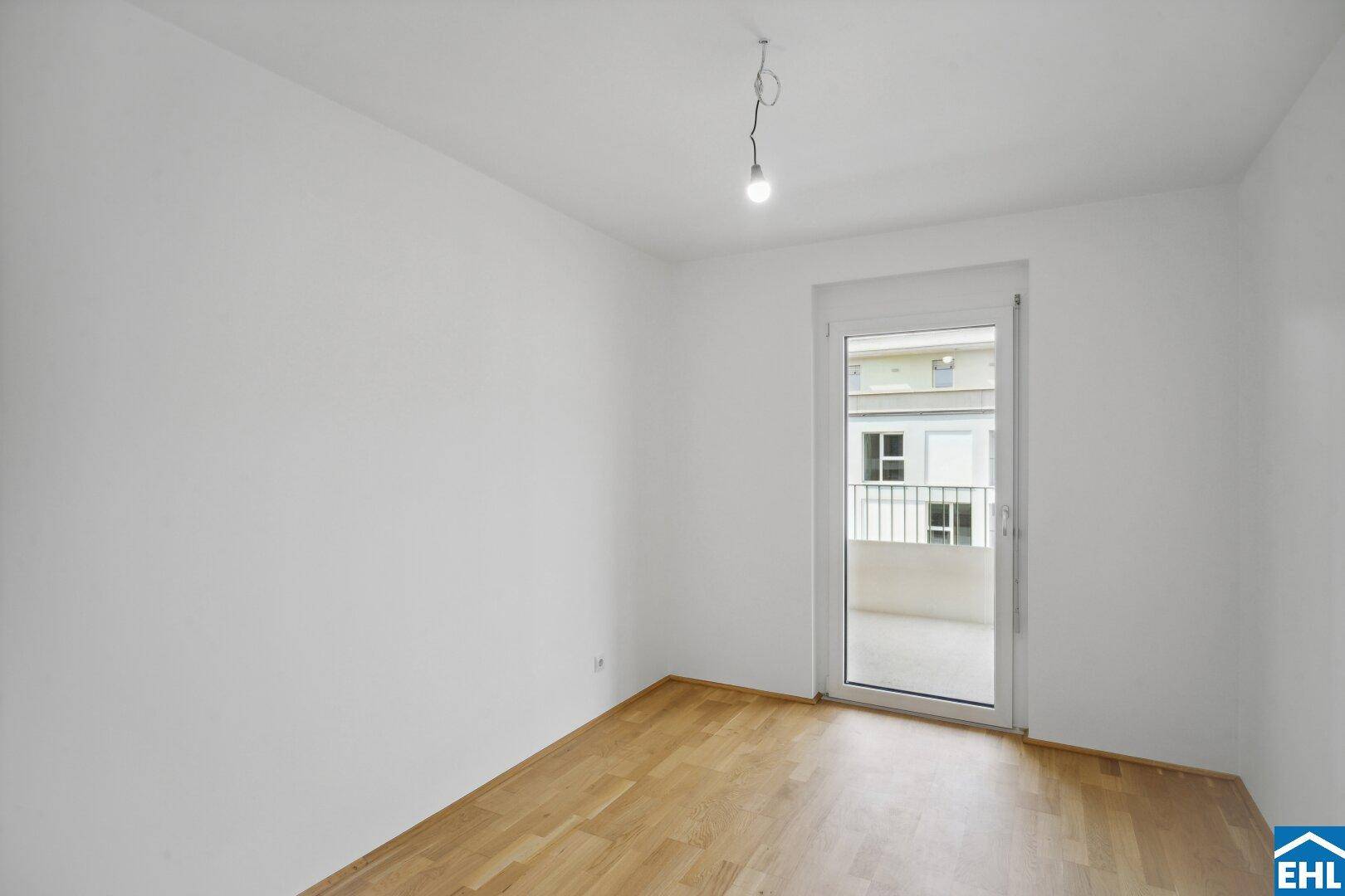 Helles Zimmer mit Holzboden und Zugang zu einem Balkon, ideal als Schlaf- oder Arbeitszimmer.