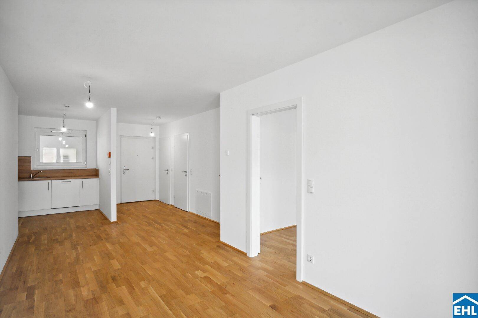 Offener Wohnbereich mit Holzboden und integrierter Küchenzeile, bietet vielseitige Gestaltungsmöglichkeiten.