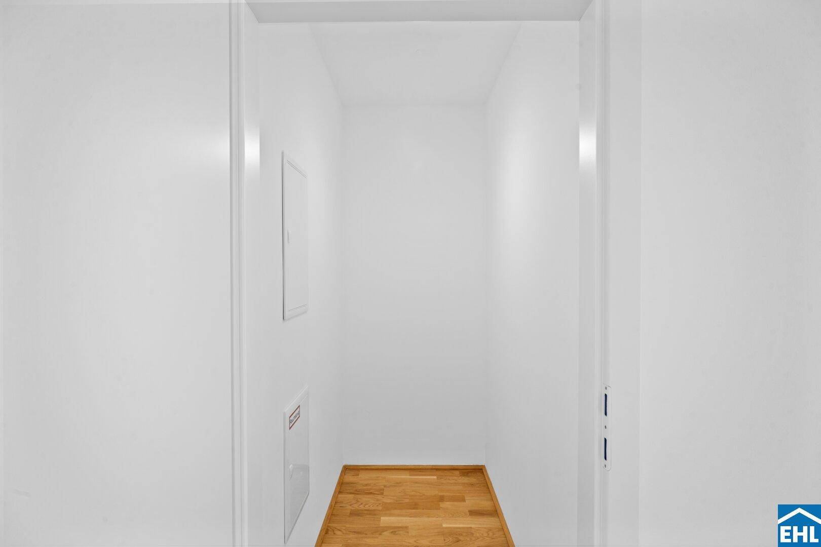 Kleiner Abstellraum mit Holzboden und weißen Wänden, ideal für Lagerung.