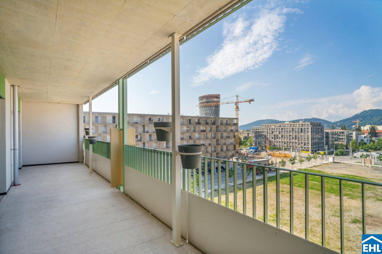 Geräumiger Balkon mit Blick auf die Stadt und die umliegenden Berge unter blauem Himmel.
