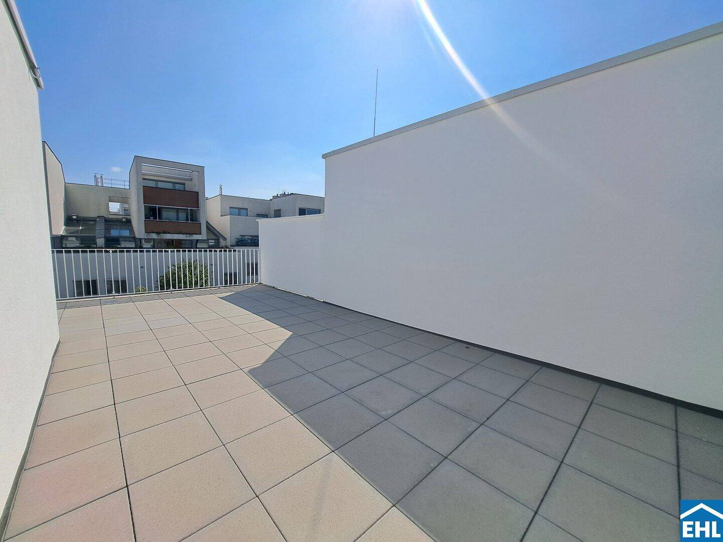 Weitläufige Terrasse mit Fliesenboden und Blick auf die umliegenden Gebäude.