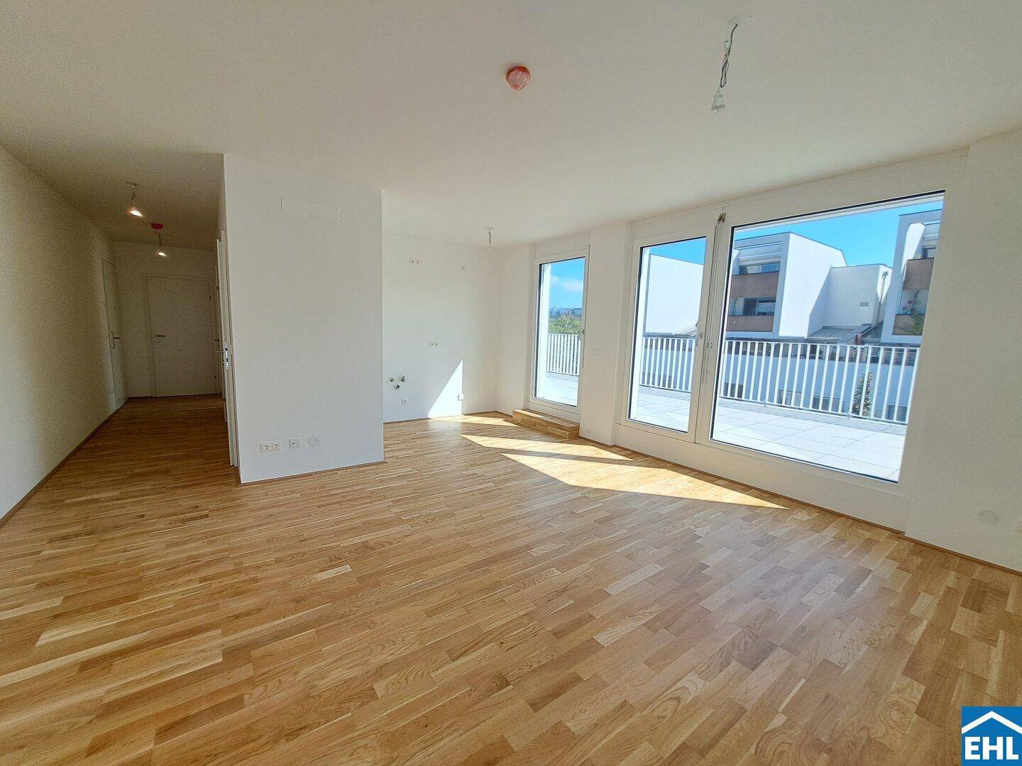 Geräumiger, heller Wohnbereich mit Parkettboden und Zugang zu einer großen Terrasse.