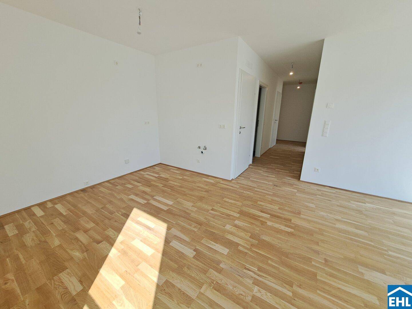 Heller Wohnbereich mit Holzboden und offenem Übergang zu einem Flur, ideal für modernes Wohnen.
