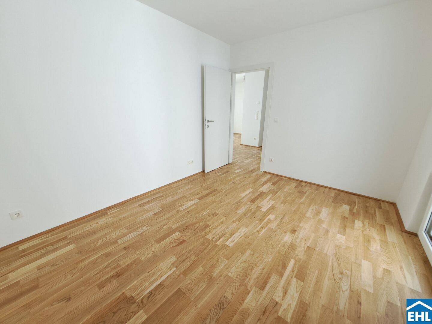 Leeres Schlafzimmer mit hellem Holzboden und weiß gestrichenen Wänden, bereit zum Einzug.