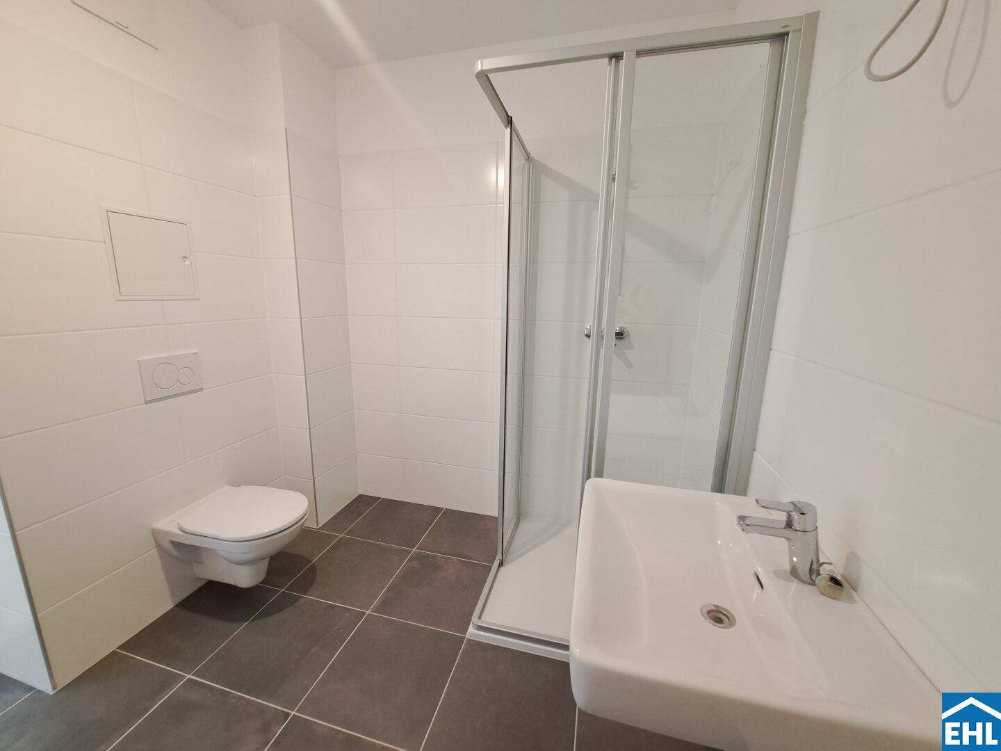 Modernes Badezimmer mit Duschkabine, wandhängendem WC und Waschbecken.