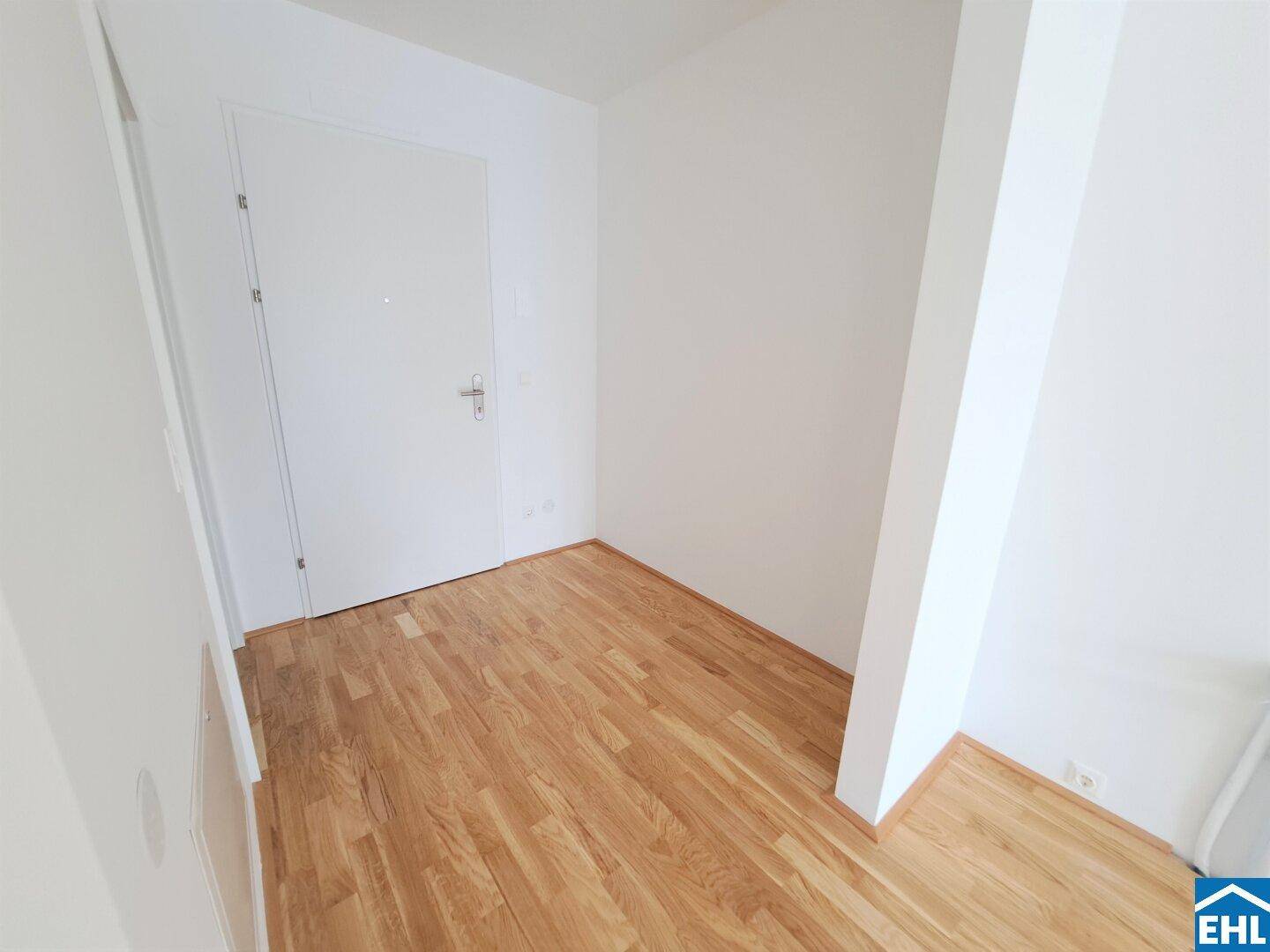 Eingangsbereich oder Flur mit Holzparkettboden und weißer Eingangstür.